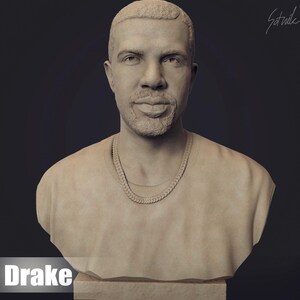 May include: A beige bust sculpture of a person with short hair, wearing a plain t-shirt and a chain necklace. The sculpture is on a beige base. The text "Drake" is below the sculpture.