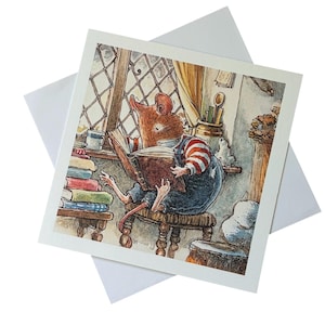Puede incluir: Una tarjeta de felicitación cuadrada con una ilustración en acuarela de un ratón marrón con mangas a rayas rojas y blancas y peto azul, sentado en un taburete de madera mientras lee un libro abierto junto a una ventana con libros.