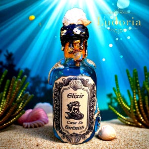 Könnte beinhalten: Eine blaue Glasflasche mit einer Muschel und einer weißen Substanz oben, beschriftet mit "Elixir Coeur De Sirènith" mit einer Meerjungfrau-Illustration. Die Flasche hat goldene Akzente und befindet sich in einer Unterwasserszene mit Sand und Korallen.