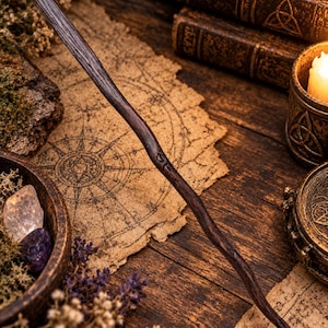 Puede incluir: Una varita de madera larga, delgada y de color marrón oscuro con una superficie natural, ligeramente curva y texturizada. La varita presenta un pequeño símbolo rúnico tallado a mano en la madera cerca del centro, con un aspecto rústico.