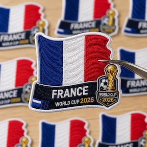 May include: Embroidered patch featuring the French flag in blue, white, and red. The patch includes the word "FRANCE" and "WORLD CUP 2026" in white text on a black banner. A gold trophy and soccer ball are also featured.