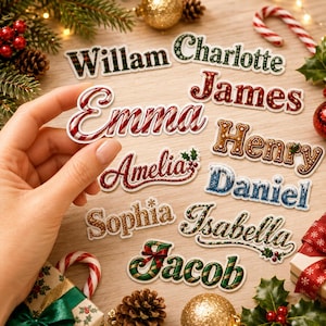 May include: A collection of die-cut Christmas-themed name stickers featuring various festive designs including candy cane stripes, gingerbread textures, glittery gold, and holly accents. The names displayed are Willam, Charlotte, James, Emma, Henry, Amelia, Daniel, Sophia, Isabella, and Jacob.