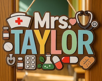 May include: A wooden door sign with the name "Mrs. TAYLOR" in colorful letters. The sign includes medical-themed icons like a nurse's hat, stethoscope, pills, and a bandage. The sign is hanging on a wooden door.