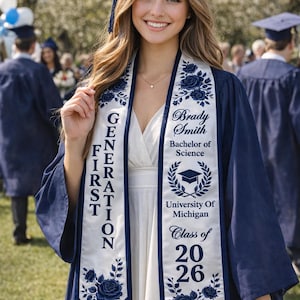 A smiling young woman in a blue graduation gown and cap stands in front of a crowd at a graduation ceremony.