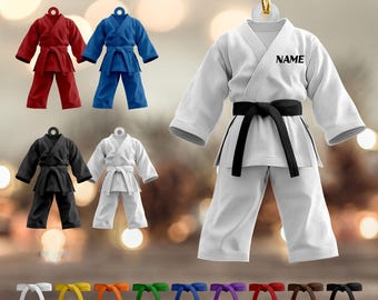 May include: Karate uniform ornaments in red, blue, black, and white, with a variety of colored belts. A white uniform with a black belt has the word "NAME" printed on it. The ornaments are designed to hang.