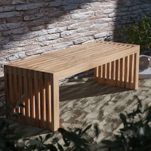 Puede incluir: Un banco de madera con un diseño de listones, hecho de madera marrón claro. El banco está situado delante de una pared de ladrillo.