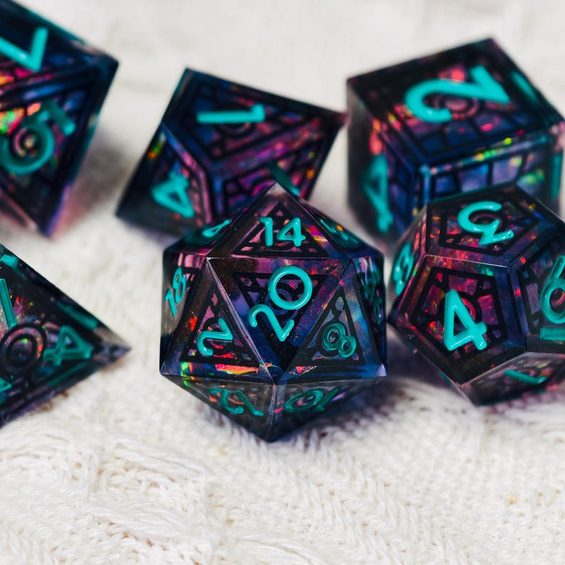May include: A set of polyhedral dice featuring a dark, translucent resin base with embedded iridescent flakes in shades of purple, blue, and pink. Each die has sharp edges and is inscribed with bright teal numbers in a clear, sans-serif font.
