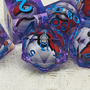May include: A set of purple and blue dice with a white and red Pokeball design. The dice are numbered 1 through 20.