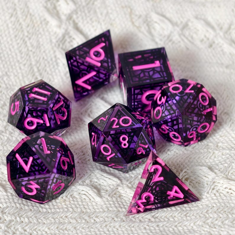 May include: A set of six polyhedral dice featuring a translucent purple resin shell with an intricate black geometric lattice pattern inside. Each die has bright pink numbers engraved on the faces, including a d20, d12, d10, d8, d6, and d4.