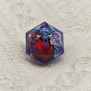 May include: A purple 20-sided die with blue numbers and a red and white Pokeball inside.