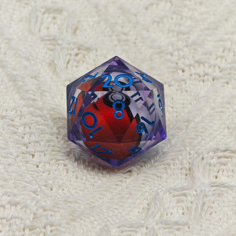 May include: A purple 20-sided die with blue numbers and a red and white Pokeball inside.