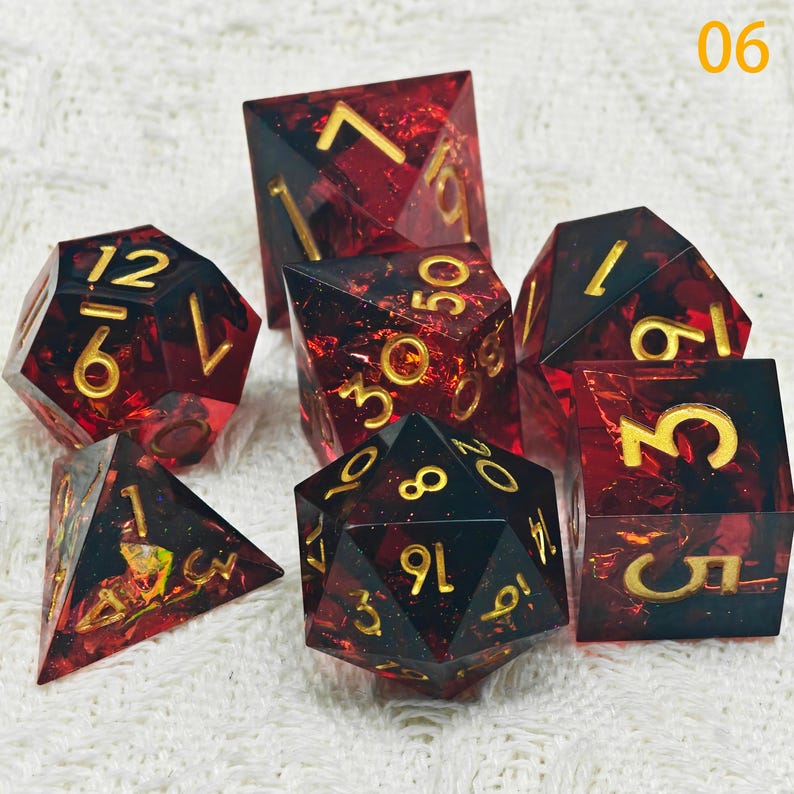 Puede incluir: Conjunto de siete dados rojos y negros con n&uacute;meros dorados. Los dados est&aacute;n hechos de pl&aacute;stico transparente con un acabado brillante. Los n&uacute;meros en los dados son 1, 2, 3, 4, 5, 6, 8, 9, 10, 12, 30, 50.