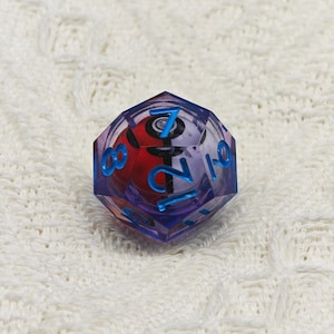 May include: A purple and blue 12-sided die with a Pokeball design and numbers 1 through 12 on the faces.
