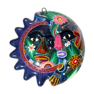 May include: A wall-hanging ceramic plaque featuring a dual-faced sun and moon design. The sun side has jagged rays and a dark blue base, while the moon side is rounded. Both faces are decorated with vibrant, multi-colored floral and bird motifs.