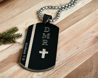 Può includere: Collana con ciondolo a forma di targhetta nera e catena argentata. La targhetta ha le lettere "DMR" incise, insieme a una piccola croce con una pietra trasparente al centro. La targhetta ha anche il testo "Joshua 1:9" inciso.
