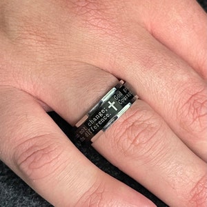 May include: A silver ring with a cross and the inscription "Do not change, God gives the difference. Courage."