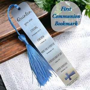 May include: A silver bookmark with a blue tassel. The bookmark has the words "Quinten you are STRONG CHOSEN MADE FOR A PURPOSE A PRECIOUS CHILD OF GOD LOVED FOREVER" and Bible verses. The words "First Communion Bookmark" are also visible.