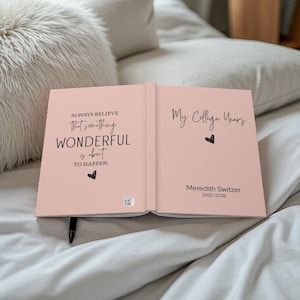 May include: Open journal with a light pink cover. The left page reads "ALWAYS BELIEVE that something WONDERFUL is about TO HAPPEN." The right page says "My College Years" with a name and dates.