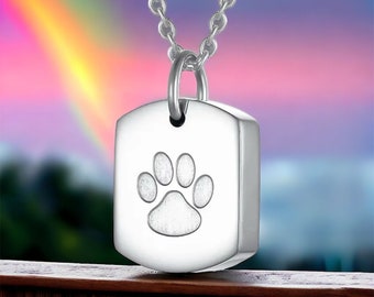 May include: Silver necklace with a square pendant featuring a paw print. The pendant is a cremation urn for holding ashes.