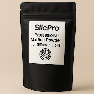 Puede incluir: Bolsa negra de SilcPro Professional Matting Powder para mu&ntilde;ecas de silicona. El nombre del producto y la descripci&oacute;n est&aacute;n impresos en blanco sobre una etiqueta blanca. Un dise&ntilde;o circular est&aacute; debajo del texto.
