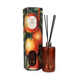 May include: A reed diffuser set featuring a tall, amber-coloured, ribbed glass bottle with black reeds and a matching hexagonal cardboard box. The box displays illustrations of oranges and green leaves with the text Mandarin & Orange Blossom.