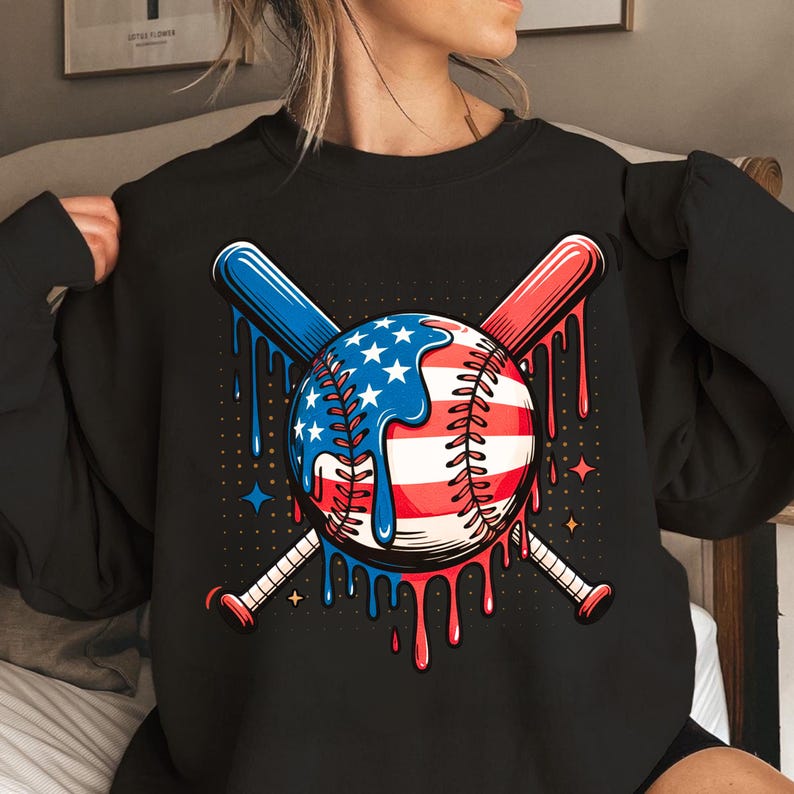 K&ouml;nnte beinhalten: Schwarzes Sweatshirt mit Baseball-Design. Der Baseball ist mit der amerikanischen Flagge und gekreuzten Baseballschl&auml;gern verziert. Das Design umfasst rote, wei&szlig;e und blaue Farben mit tropfenden Farbeffekten.