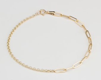 May include: A gold-colored bracelet featuring two distinct chain styles. One side has a delicate, rounded chain, while the other showcases a series of elongated, rectangular links. The bracelet is secured with a lobster clasp.