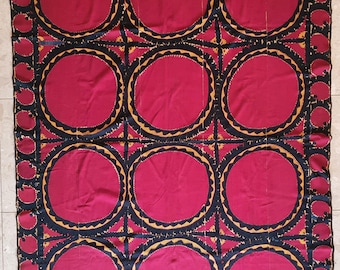 May include: A large, rectangular textile with a repeating pattern of burgundy circles. Each circle is outlined with a black border, a gold scalloped edge, and a dark blue border. The edges feature smaller, decorative burgundy shapes.
