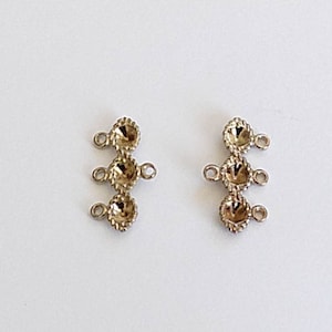 May include: Two gold-toned metal jewelry connectors with three round loops each. The loops are connected by a decorative design.
