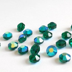 May include: A scattering of emerald green faceted glass beads, each with a slightly iridescent finish.