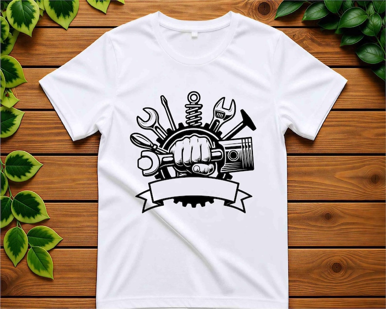 Pode incluir: Uma t-shirt branca de manga curta com uma impress&atilde;o gr&aacute;fica preta de um punho cerrado segurando uma chave inglesa, rodeado por ferramentas mec&acirc;nicas, incluindo uma engrenagem, um pist&atilde;o, uma chave de fendas e uma chave, com uma faixa vazia na parte inferior.