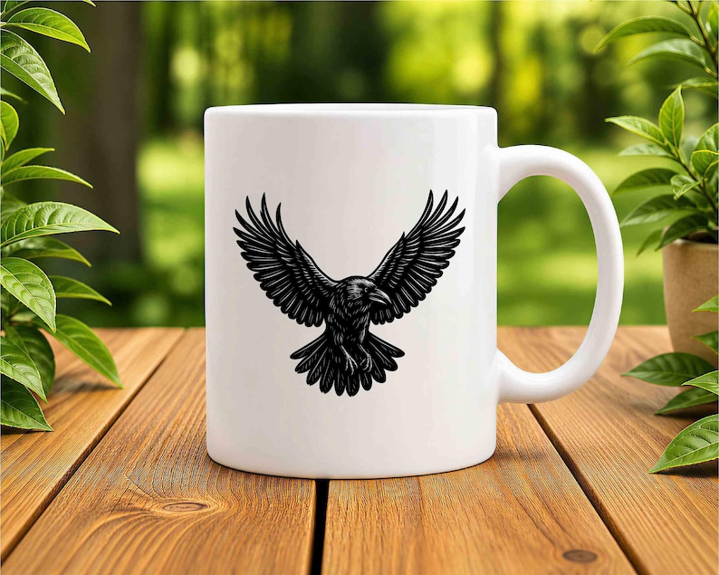 May include: A white ceramic mug featuring a black graphic illustration of a raven with its wings spread wide in flight. The bird is depicted in a detailed, etched style centered on the front of the mug, which has a smooth finish and a handle.