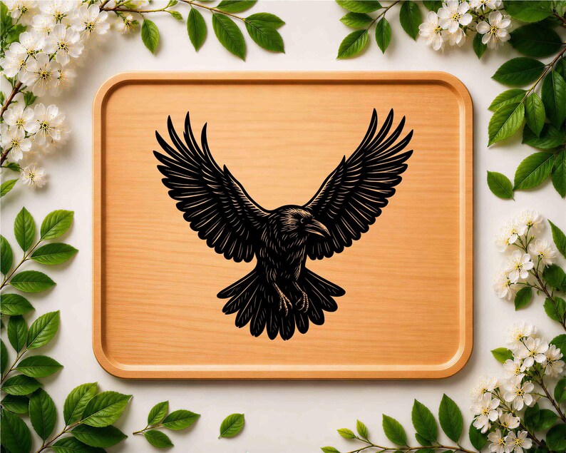 May include: A rectangular light brown wooden serving tray featuring a centered black graphic illustration of a raven with its wings spread wide in flight. The bird is depicted with detailed feather textures and a sharp beak facing to the right.