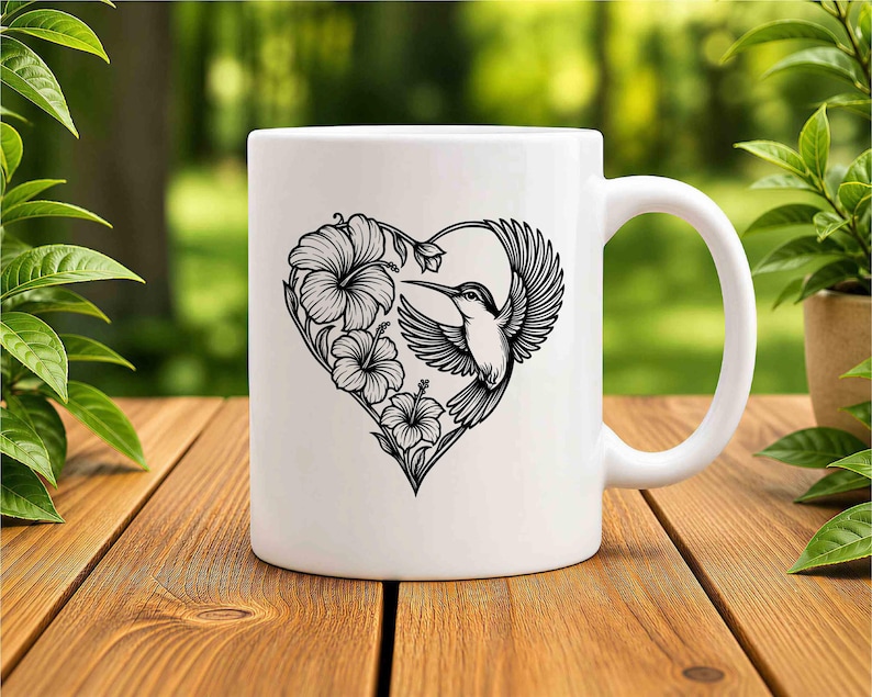 K&ouml;nnte beinhalten: Ein wei&szlig;er Keramikbecher mit einer schwarzen Strichzeichnung eines Kolibris und Hibiskusbl&uuml;ten, die in Herzform angeordnet sind. Das Motiv ist mittig auf der Vorderseite des Bechers platziert, der eine glatte Oberfl&auml;che und einen geschwungenen Henkel hat.