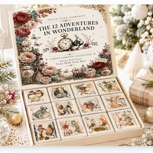 May include: A gift box set titled The 12 Adventures in Wonderland by Field Soap Company, containing twelve square goat milk soap bars. Each bar features a unique illustration and a number from 1 to 12, arranged in a grid within the open box.