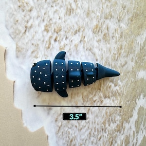 May include: A blue and white whale shark toy with white polka dots. The toy is 3.5 inches long.
