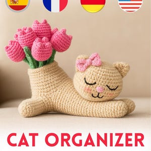 May include: A crocheted cat organizer with a pink bow and closed eyes, holding a vase of pink crocheted tulips. The text "CAT ORGANIZER CROCHET PATTERN" is displayed in red. The cat and vase are beige.