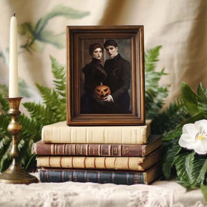 May include: A framed portrait of a couple holding a carved pumpkin, resting on a stack of vintage books. The frame is dark brown, and the portrait features the couple in dark attire. A brass candlestick with a white candle is on the left.