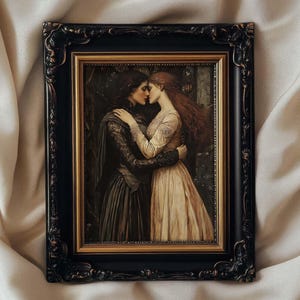 May include: A framed artwork depicts two figures embracing and kissing. The painting features a dark-haired figure in a dark gown and a red-haired figure in a cream-colored dress. The frame is black with ornate detailing and a gold inner border.