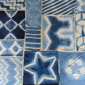 Indigo Dyed Fabrics lay flat on a table top. Cotton, Silk and Rayon were folded and dyed to create an array of geometric and crystalline textures in Indigo and White. Graham Keegan Natural Indigo and Shibori Dye Kit was used  to dye each of them.