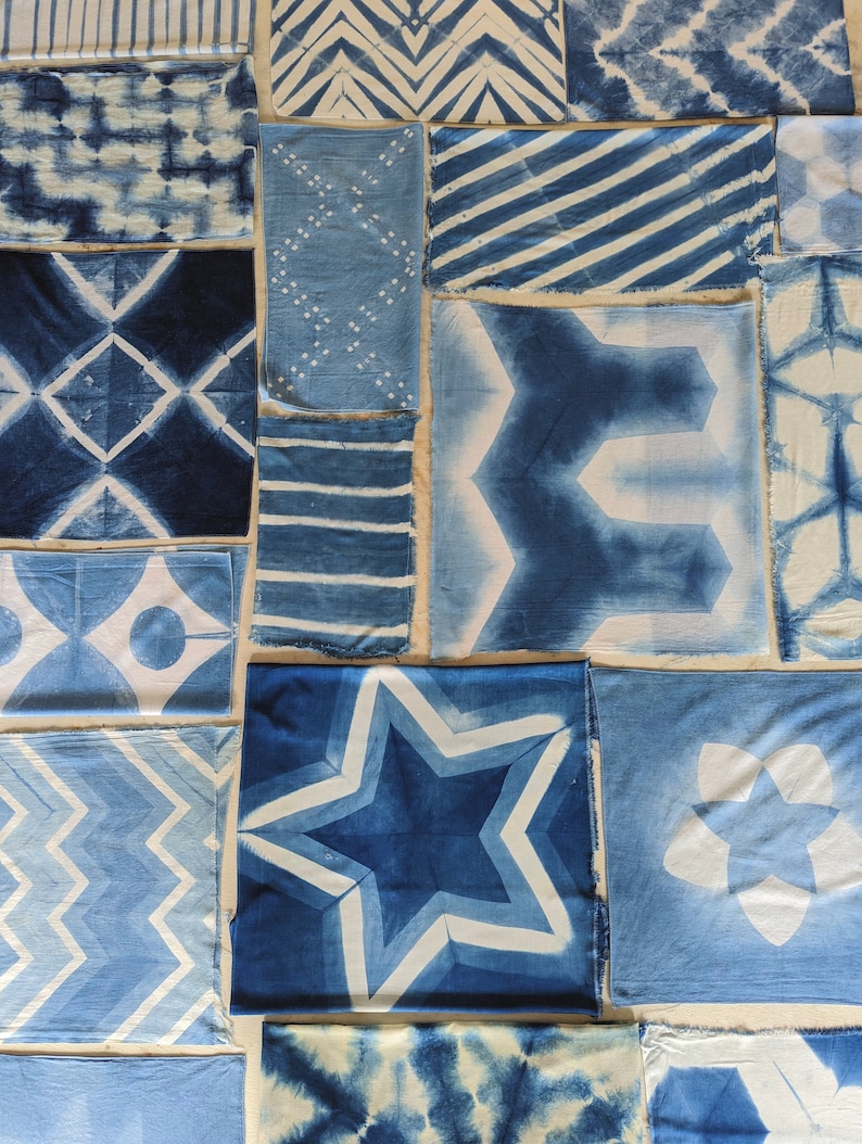 Indigo Dyed Fabrics lay flat on a table top. Cotton, Silk and Rayon were folded and dyed to create an array of geometric and crystalline textures in Indigo and White. Graham Keegan Natural Indigo and Shibori Dye Kit was used  to dye each of them.