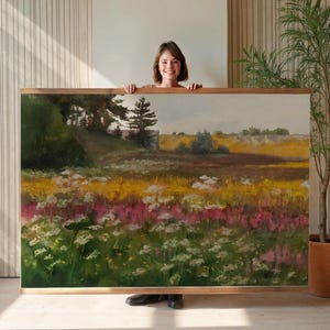 Puede incluir: Pintura de paisaje enmarcada, que representa un campo de flores silvestres en tonos amarillos, rosas y blancos. La obra muestra colinas y un cielo azul. El marco es de madera.