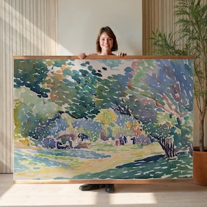 May include: A large landscape painting in a wooden frame. The artwork depicts a park scene with trees, figures, and a grassy area, rendered in shades of green, blue, and yellow. The painting is held by a person.