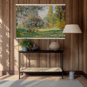 Pode incluir: Uma pintura de paisagem emoldurada retratando uma cena de parque com &aacute;rvores, flores e um edif&iacute;cio ao fundo. Abaixo, uma consola preta com um banco tecido e vasos decorativos. &Agrave; direita, uma lumin&aacute;ria de ch&atilde;o com abajur bege.