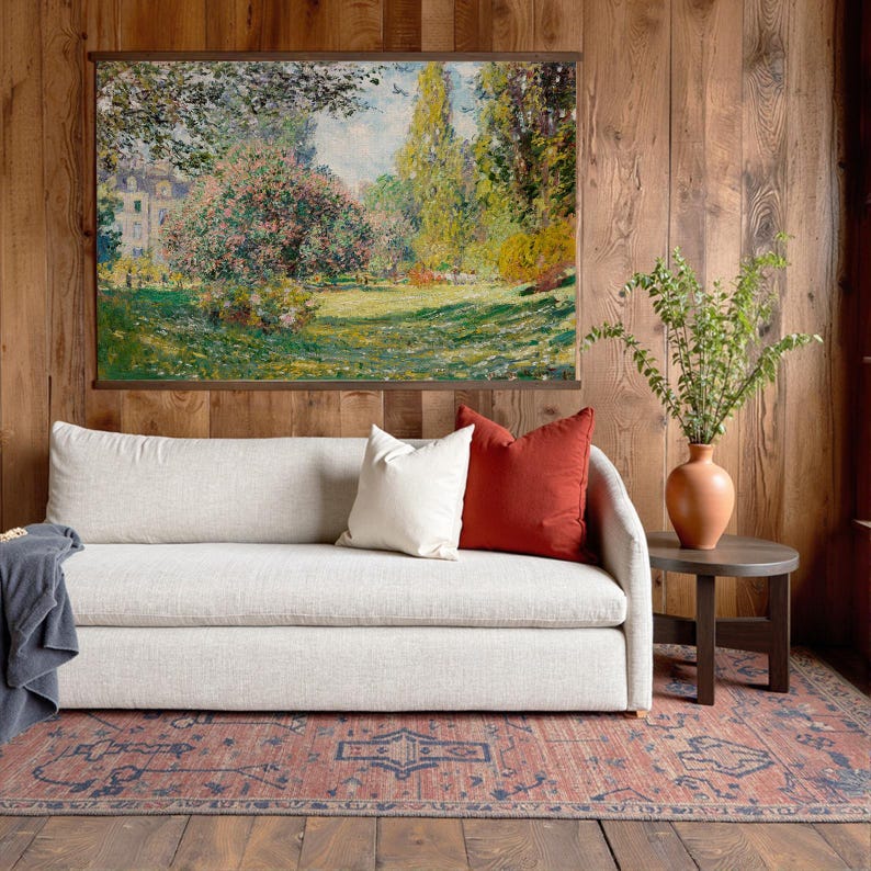 Pode incluir: Uma sala de estar com um sof&aacute; de cor clara adornado com almofadas brancas e cor de ferrugem. Uma pintura de paisagem emoldurada est&aacute; pendurada acima do sof&aacute;. Um vaso de terracota com vegeta&ccedil;&atilde;o est&aacute; em uma pequena mesa lateral. Um tapete estampado e pain&eacute;is de madeira completam a decora&ccedil;&atilde;o.