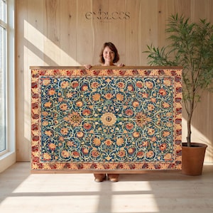 May include: A framed, rectangular rug with a detailed floral pattern in shades of blue, red, and gold. The rug is held up by a person. The word "ENDLESS" is visible in the background.