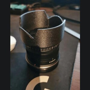 Op de afbeelding: Een zwarte camera lens met een zwarte lenskap. De lens heeft een zilveren band met het woord "Canon" erop gedrukt.