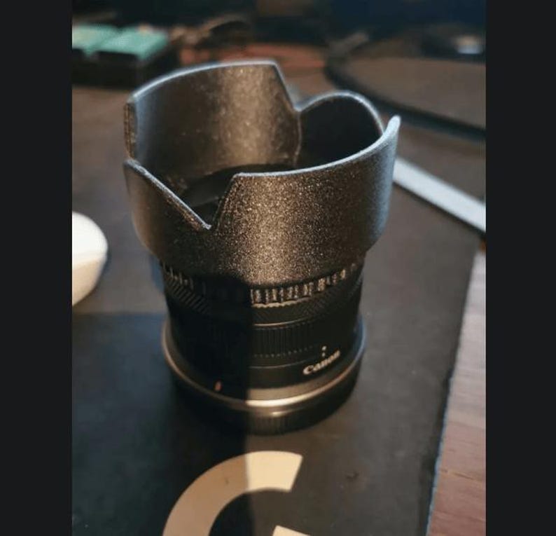 Op de afbeelding: Een zwarte camera lens met een zwarte lenskap. De lens heeft een zilveren band met het woord "Canon" erop gedrukt.