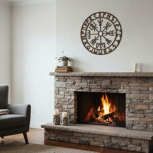 Peut inclure: Un salon confortable avec une chemin&eacute;e en pierre et un feu qui br&ucirc;le. Au-dessus de la chemin&eacute;e, une d&eacute;coration murale circulaire et marron avec des symboles complexes. Un fauteuil gris avec une couverture est &agrave; gauche.