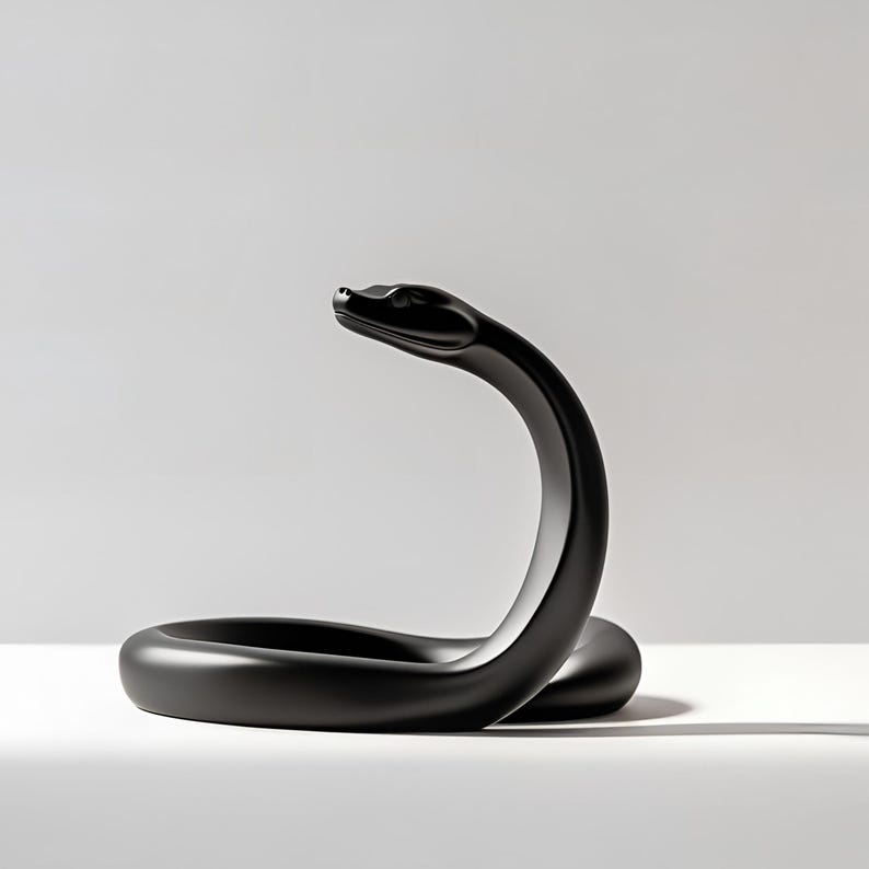 Puede incluir: Una escultura negra mate de una serpiente en una pose llamativa. El cuerpo de la serpiente est&aacute; enrollado, con la cabeza levantada y ligeramente curvada. La escultura se encuentra sobre un fondo blanco, resaltando su dise&ntilde;o elegante.